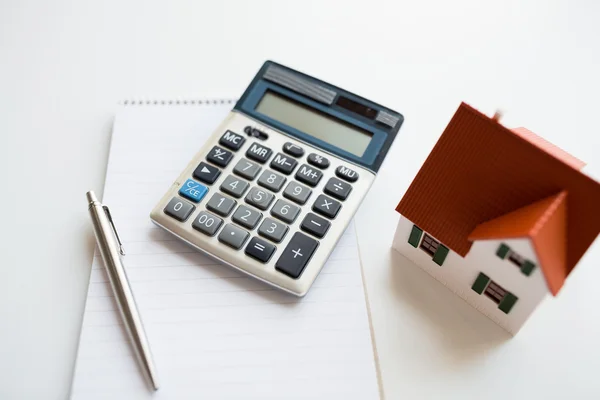 Close-up de casa modelo, calculadora e notebook — Fotografia de Stock