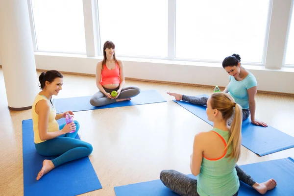 Glada gravida kvinnor sitter på mattor i gym — Stockfoto