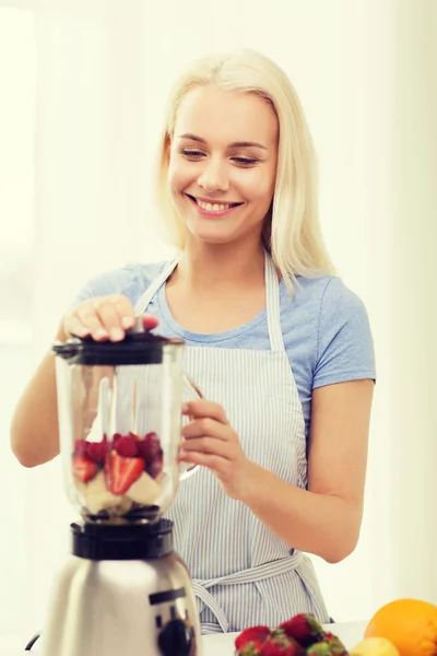 Mulher sorridente com liquidificador preparando shake em casa — Fotografia de Stock