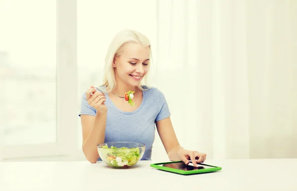 Mulher sorrindo comer salada com tablet pc em casa — Fotografia de Stock