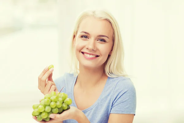 Gelukkige vrouw druiven eten thuis — Stockfoto