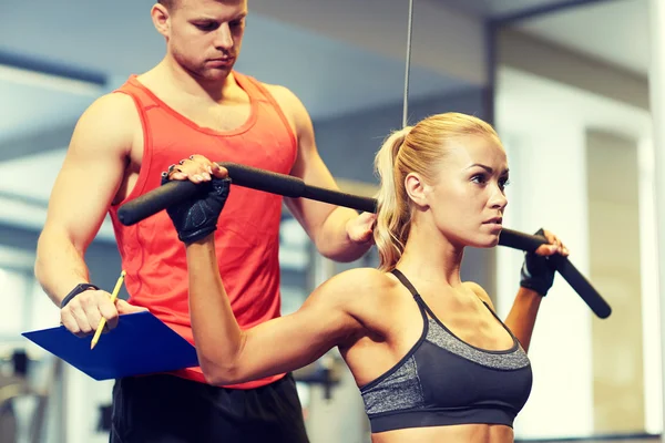 Man and woman flexing muscles on gym machine — Stock Photo, Image