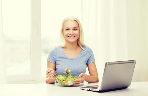 Gülümseyen kadın salata dizüstü bilgisayar ile evde yemek — Stok fotoğraf