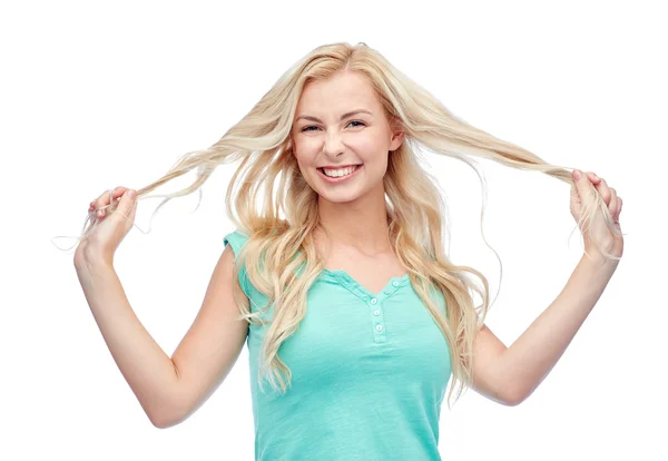 Sonriente joven mujer sosteniendo hebras de su cabello — Foto de Stock