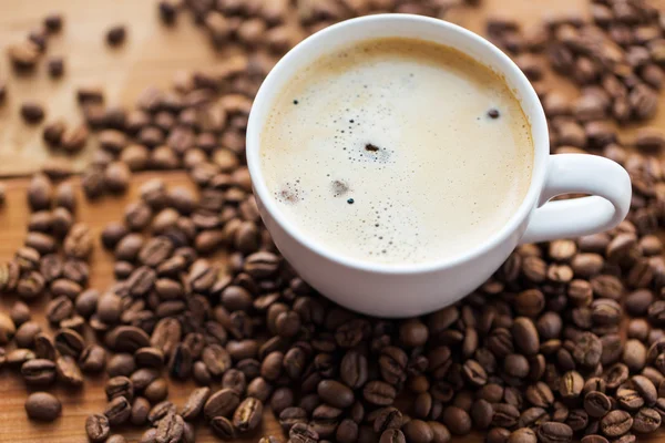 Close up coffee cup and grains on wooden table — Stock Photo, Image