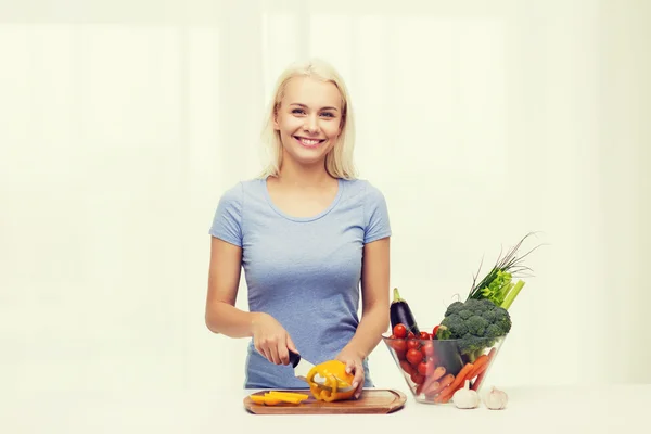 Sorrindo jovem mulher cortando legumes em casa — Fotografia de Stock