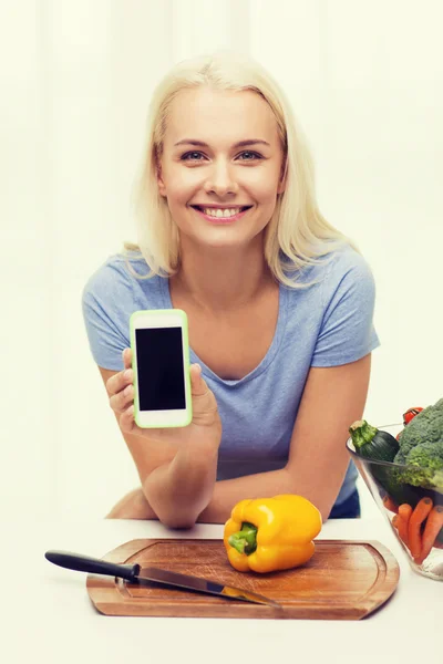 Mulher sorridente com smartphone cozinhar legumes — Fotografia de Stock