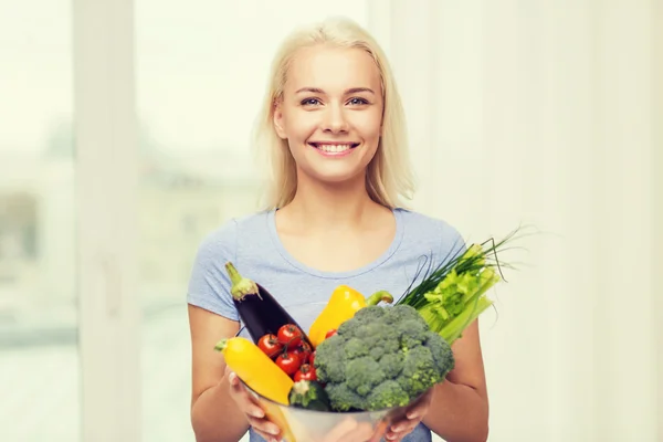 Smiling young woman with vegetables at home — Stock Photo, Image