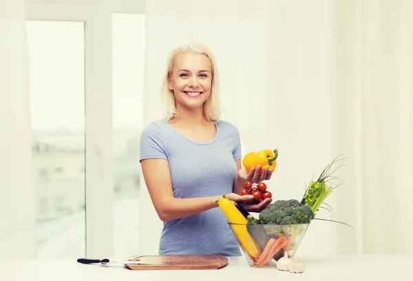 Jonge vrouw groenten thuis koken glimlachen — Stockfoto