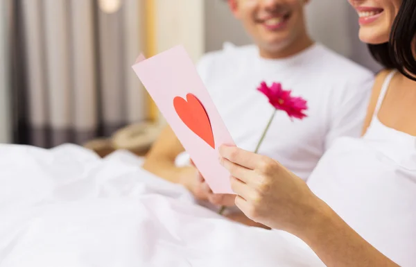 Close up de casal na cama com cartão postal e flor — Fotografia de Stock