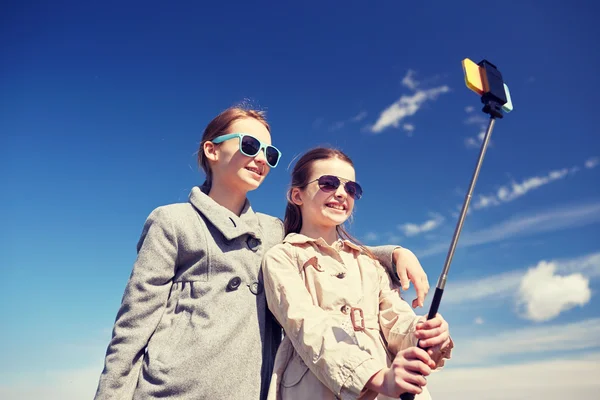 Glada tjejer med smartphone selfie pinne — Stockfoto