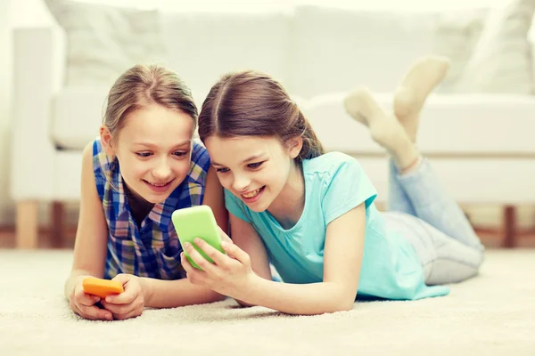 Šťastné holky s chytrými telefony, ležící na podlaze — Stock fotografie