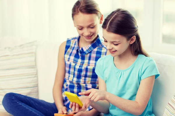 Happy girls with smartphones sitting on sofa — Stock Photo, Image