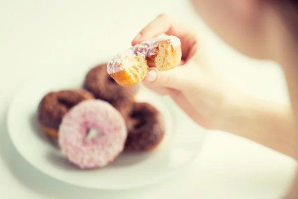 Primer plano de la mano que sostiene la rosquilla vidriada mordida — Foto de Stock