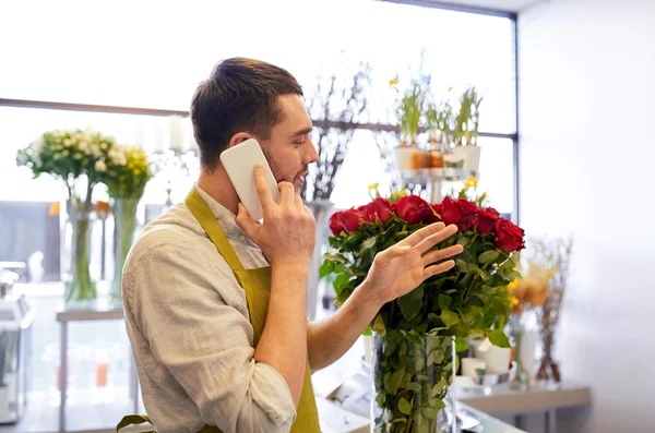 Hombre con smartphone y rosas rojas en floristería —  Fotos de Stock