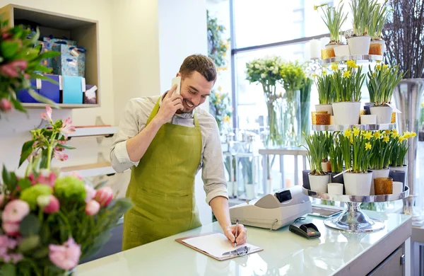 Homem com smartphone fazendo notas na loja de flores — Fotografia de Stock