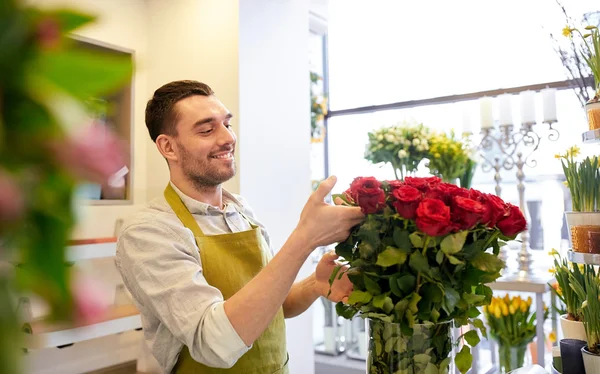 Homem florista sorridente com rosas na loja de flores — Fotografia de Stock