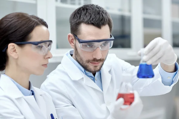 Jóvenes científicos haciendo pruebas o investigaciones en laboratorio — Foto de Stock