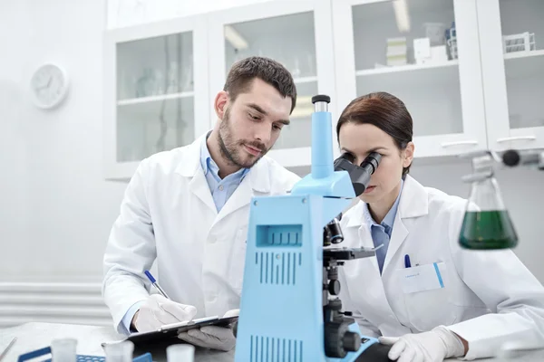 Jóvenes científicos haciendo pruebas o investigaciones en laboratorio — Foto de Stock