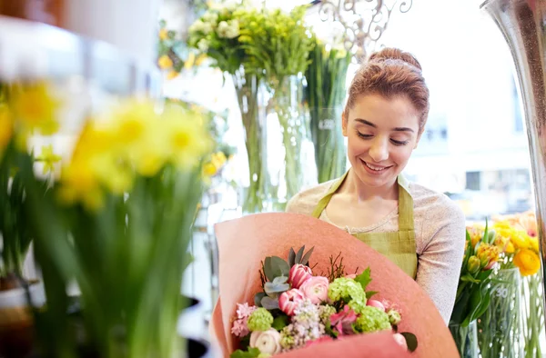 Улыбающаяся цветочница с кучей цветов в цветочном магазине — стоковое фото
