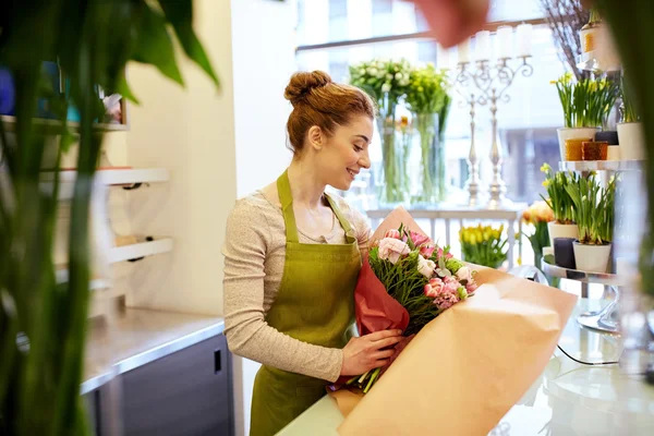 Sorridente florista mulher embalagem monte na loja de flores — Fotografia de Stock