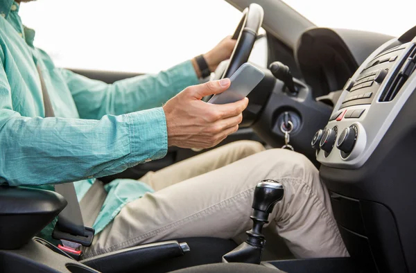 Close up of man with smartphone driving car — Stock Photo, Image