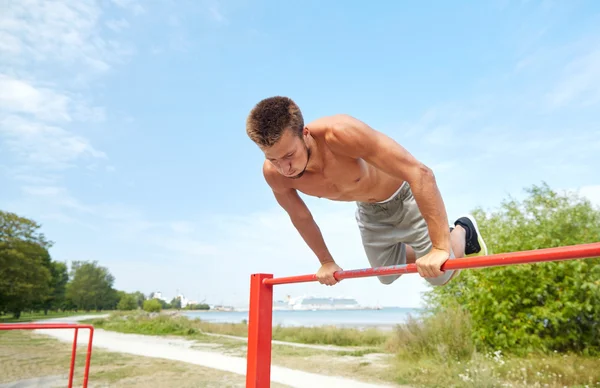 Jongeman die buiten op de horizontale balk traint — Stockfoto