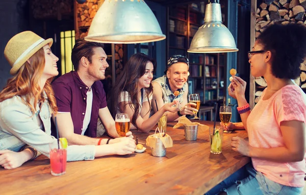 Amigos felizes com bebidas conversando no bar ou pub — Fotografia de Stock