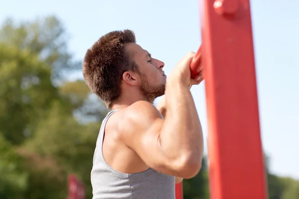 Young man exercising on horizontal bar outdoors — Stock Photo, Image