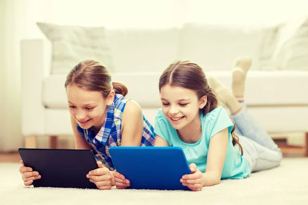 Счастливые девочки с планшетным компьютером, лежащим на полу дома — стоковое фото
