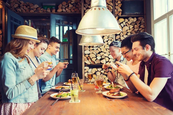Счастливые друзья со смартфонами, представляющие еду — стоковое фото