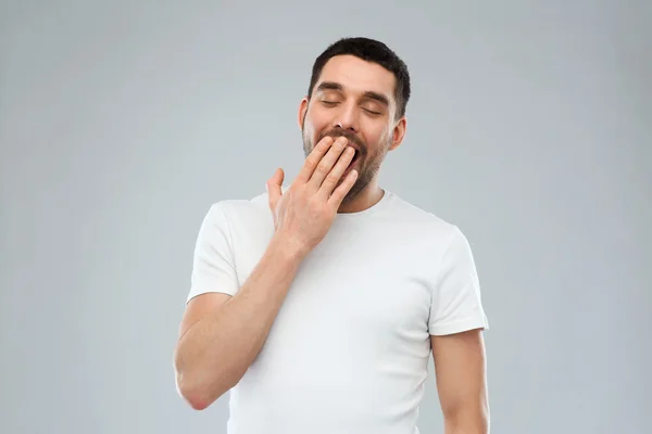 Sbadigliare l'uomo su sfondo grigio — Foto Stock