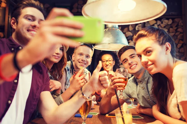 Amigos felizes com smartphone tomando selfie no bar — Fotografia de Stock