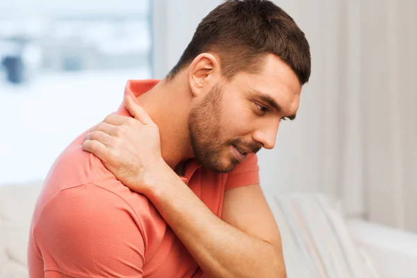 Unhappy man suffering from neck pain at home — Stock Photo, Image