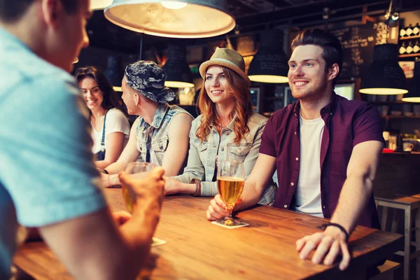 Glada vänner dricker öl och pratar på bar — Stockfoto