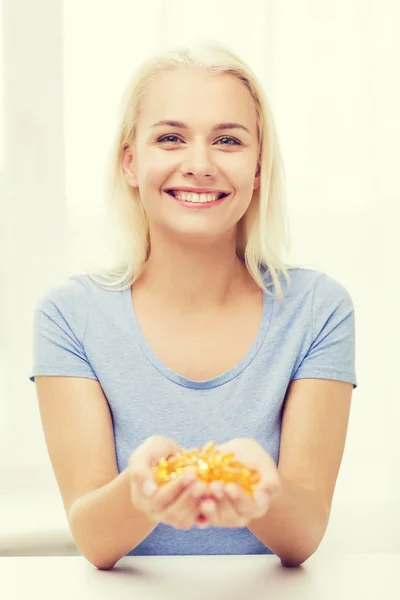 Happy woman holding fish oil capsules at home — ストック写真