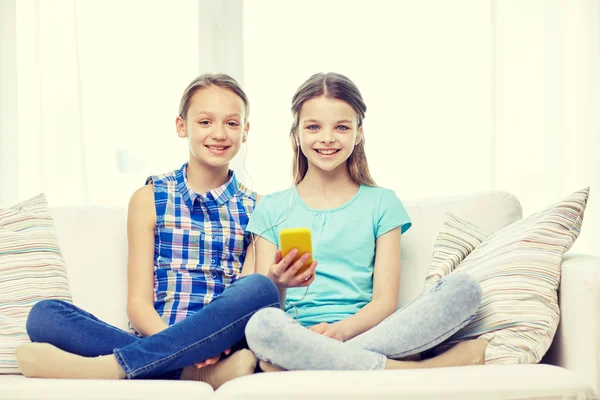 Meninas felizes com smartphone sentado no sofá — Fotografia de Stock