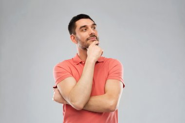 man in polo t-shirt thinking over gray background clipart