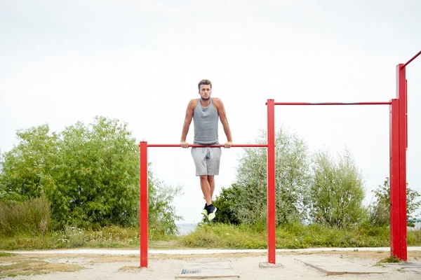 Ung man tränar på vågrät bar utomhus — Stockfoto