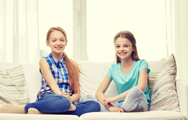Happy little girls sitting on sofa at home — Stok fotoğraf