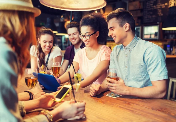 Amigos felizes com tablet pc e bebidas no bar — Fotografia de Stock