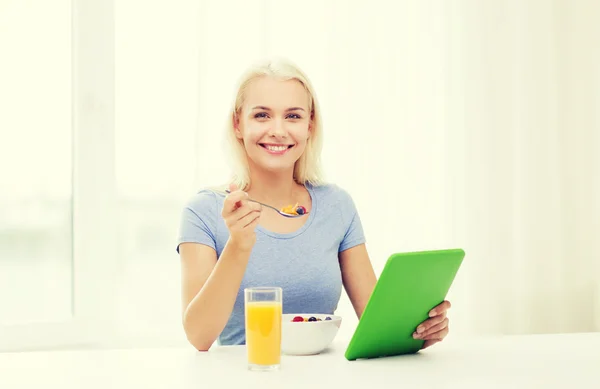 Smiling woman with tablet pc eating breakfast — Stock Photo, Image