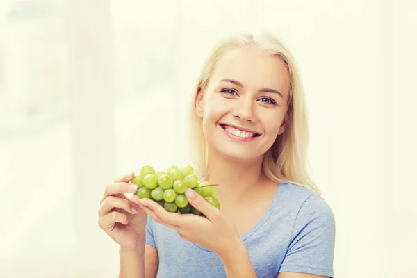 Mulher feliz comendo uvas em casa — Fotografia de Stock