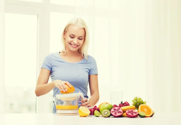 Smiling woman squeezing fruit juice at home — Zdjęcie stockowe