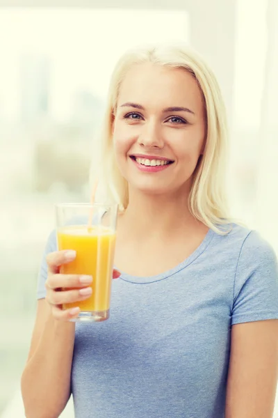 Mulher sorridente bebendo suco de laranja em casa — Fotografia de Stock