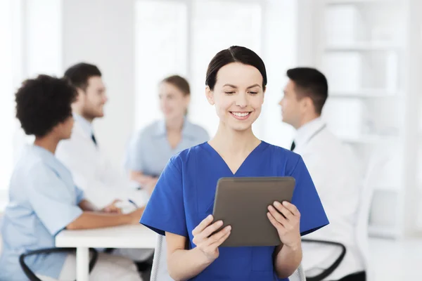 Medico felice con tablet pc sopra il team in clinica — Foto Stock