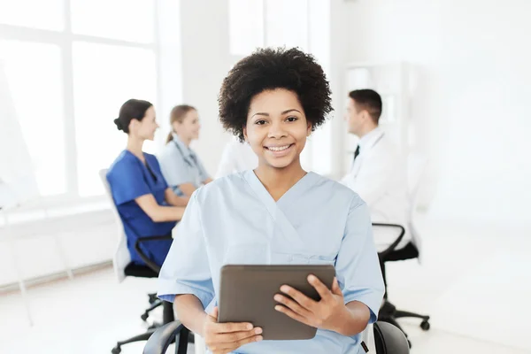 Happy sjuksköterska med TabletPC över laget på sjukhus — Stockfoto