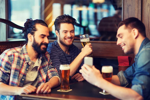Чоловіки друзі зі смартфоном п'ють пиво в барі — стокове фото