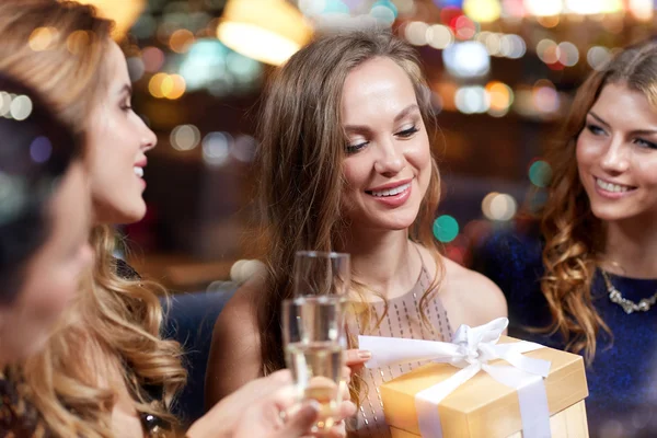 Femmes heureuses avec champagne et cadeau au night club — Photo