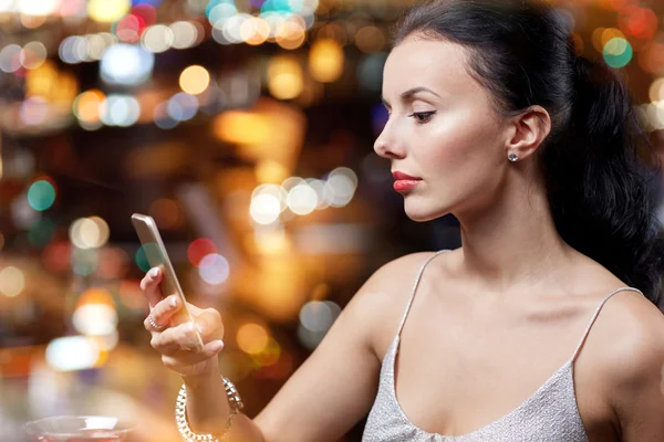 Young woman with smartphone at night club or bar — Stock Photo, Image